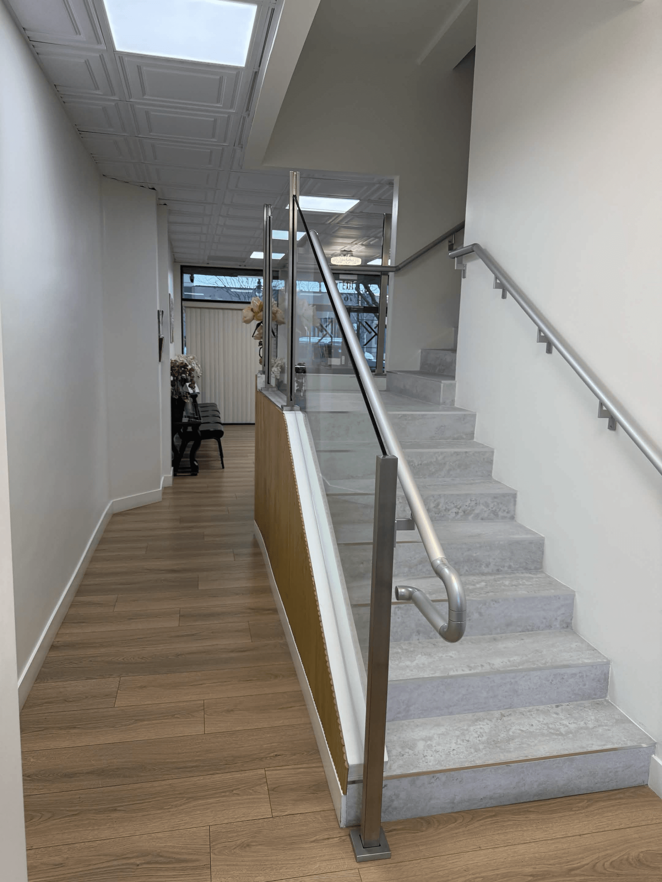 Interior stairway and hallway with glass railing and ceiling lights.